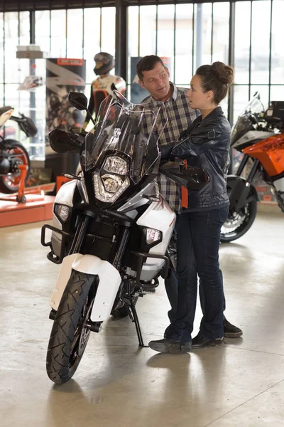 Vendedor feminino e cliente masculino perto de motocicleta na loja — Fotografia de Stock