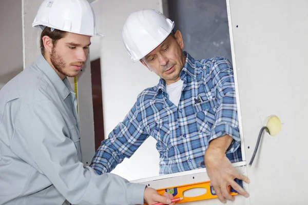 Bouwer en architect inspectie zelfs niveau van muur — Stockfoto