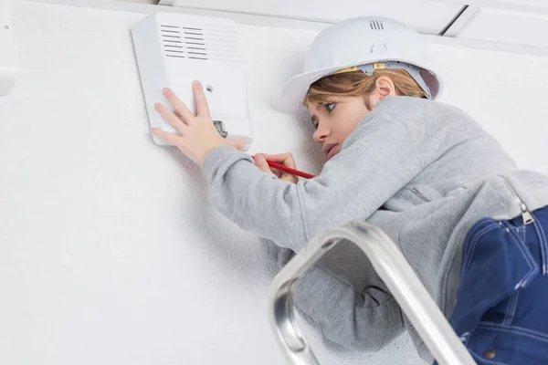 Jovem eletricista feminino em hardhat escalando a escada rolante — Fotografia de Stock