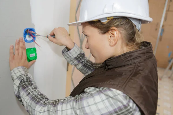 Vrouwelijke elektricien vaststelling stopcontact elektriciteit probleem — Stockfoto