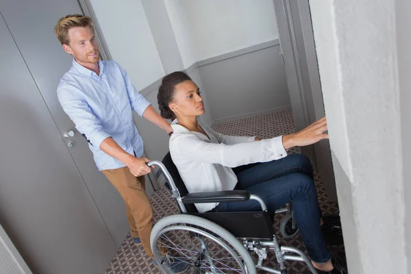 Kobieta na wózek inwalidzki, naciskając przycisk podnośnika — Zdjęcie stockowe