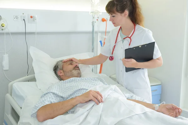 Verpleegkundige holding sicks man voorhoofd — Stockfoto