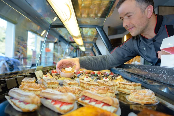 Chef de pastelaria francesa coloca sobremesas no balcão de exposição — Fotografia de Stock