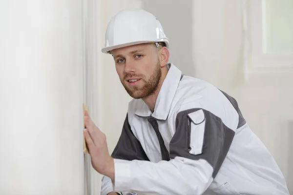 Male plasterer in uniform polishing the wall — Stock Photo, Image