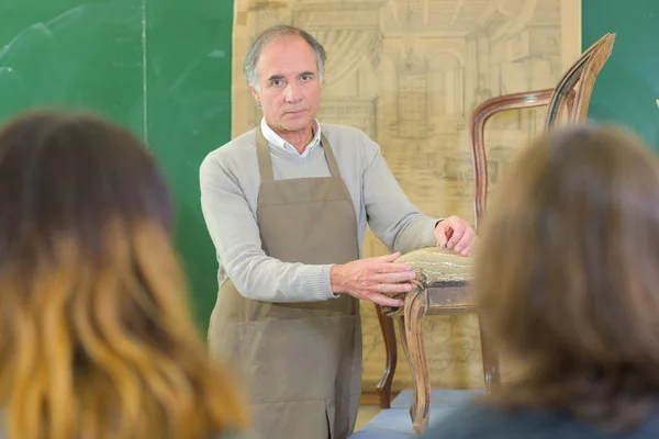 Man showing apprentice upholstering a chair — Stock Photo, Image