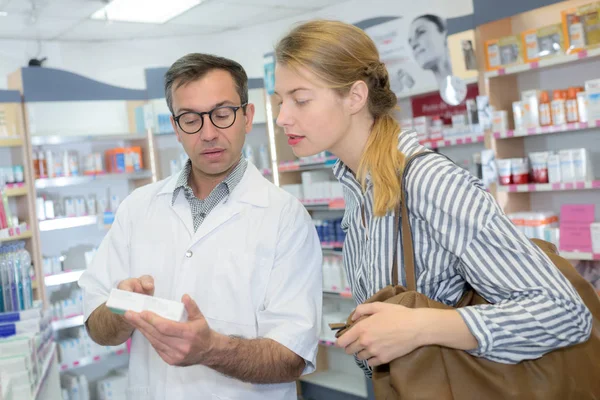 Farmacêutico ler informações sobre uma caixa para o cliente — Fotografia de Stock