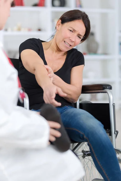 Woman with painful arm at doctors office — Stock Photo, Image