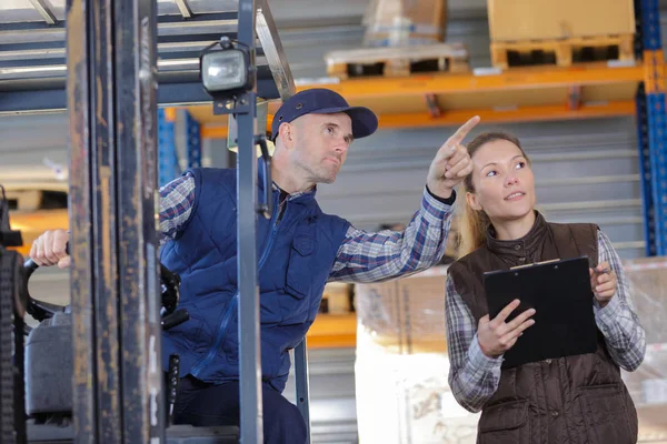 Trabajador de almacén hablando con conductor de carretilla elevadora en almacén — Foto de Stock