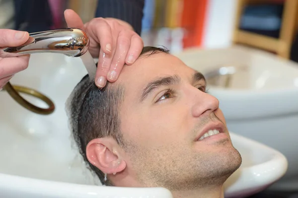 Młody człowiek wypoczywa w beauty salon fryzjerski — Zdjęcie stockowe