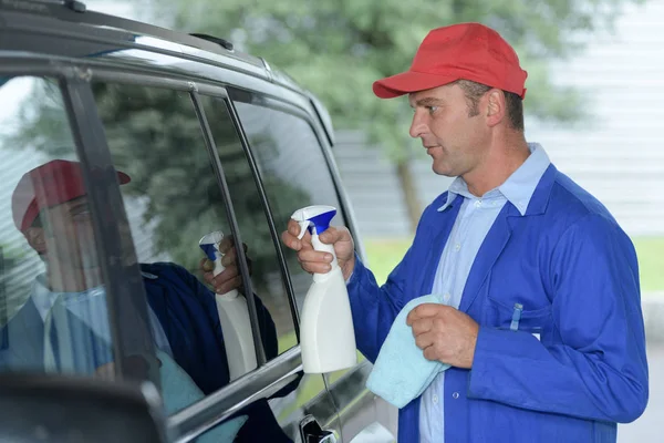 Trabajador masculino limpiando el parabrisas del coche con tela y aerosol —  Fotos de Stock
