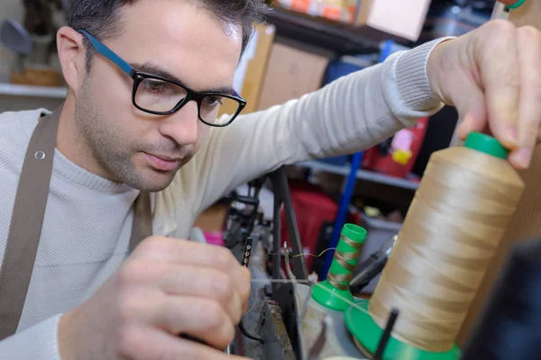 Shoemaker putting thread in the needle in workshop — Stock Photo, Image