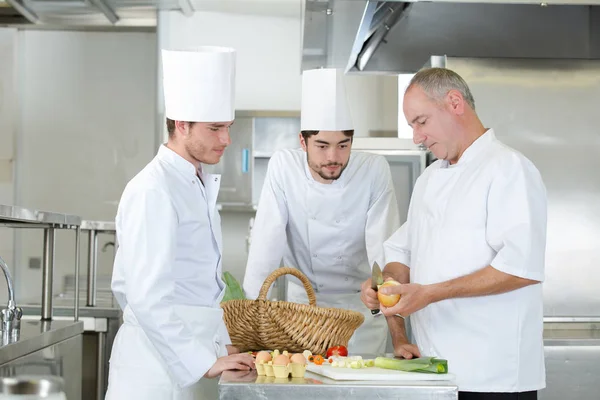 Chef et apprentis cuisiniers travaillant ensemble dans la cuisine du restaurant — Photo