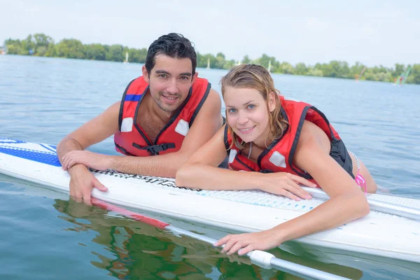 Paar lehnt an Bord im Wasser — Stockfoto