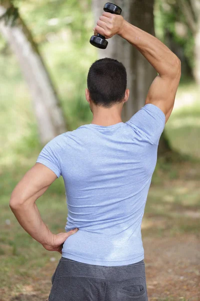 Handsome man with dumbbells standing outdoors — Stock Photo, Image