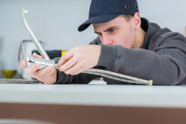 Handsome young plumber fixing tap at cleints home — Stock Photo, Image