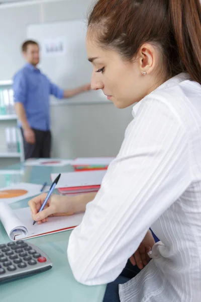 Male teacher at whiteboard fmale student taking notes — Stock Photo, Image