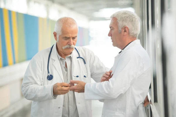 Médico passando objeto ao colega — Fotografia de Stock