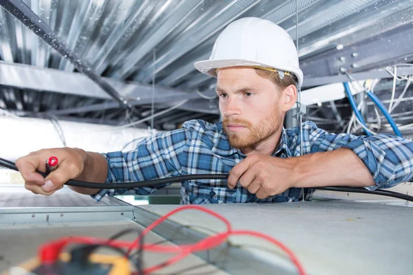 Elektricien bereiken in de ruimte van het dak — Stockfoto