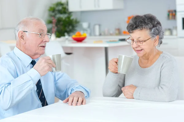 Feliz pareja de ancianos sentados en la mesa y tomando café —  Fotos de Stock