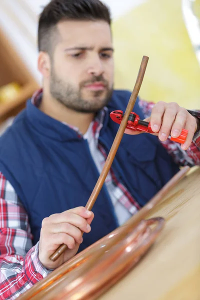 Man cutting pipes for water system  at construction site — Stock Photo, Image