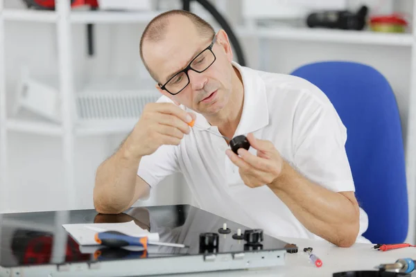 Mature repairman examining stove in kitchen — Stock Photo, Image