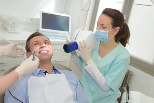 Vrouwelijke tandartsen werken op jonge mannelijke patiënt tandartsen office — Stockfoto