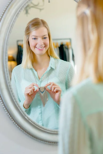 Žena se snaží na náhrdelník před zrcadlem — Stock fotografie