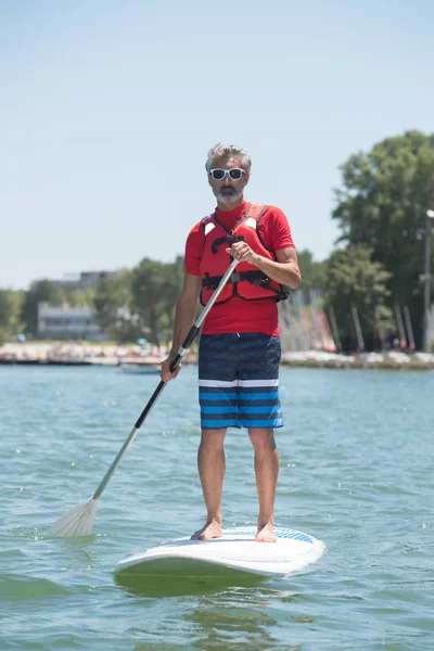 Ember élvezi egy kört a tó paddleboard — Stock Fotó