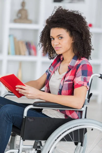 Νεαρή γυναίκα ανησυχούν σε αναπηρική καρέκλα, κρατώντας το βιβλίο — Φωτογραφία Αρχείου