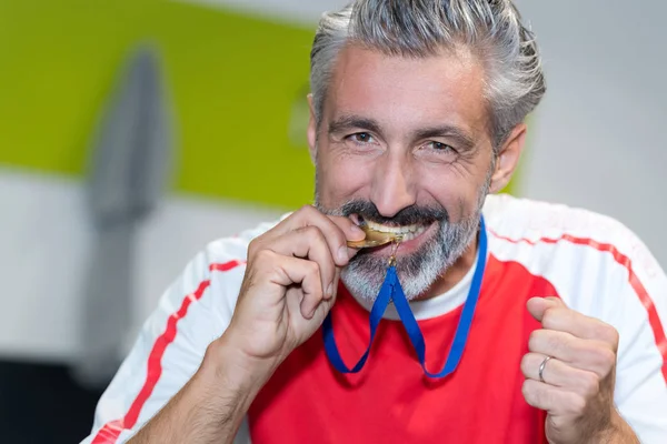 Homem mordendo a medalha de ouro — Fotografia de Stock