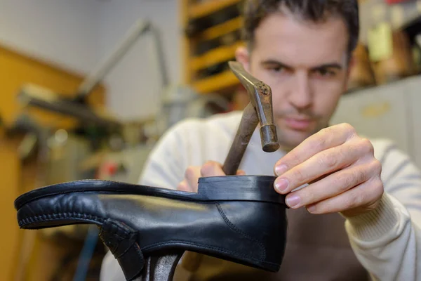 Shoemaker hammering on a shoe in workshop — Stock Photo, Image