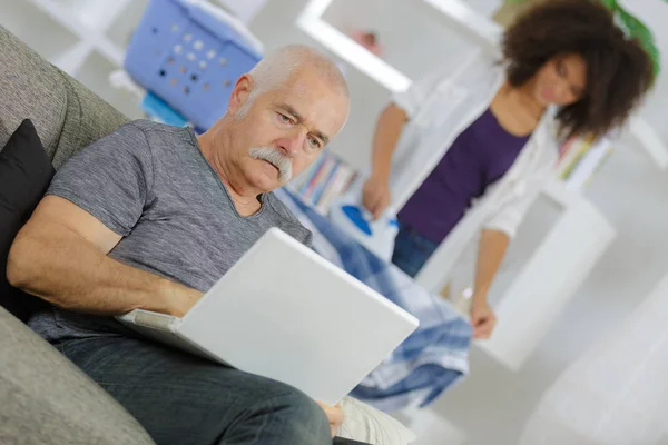 Homem sênior com laptop em casa e assistente de ajuda em casa — Fotografia de Stock