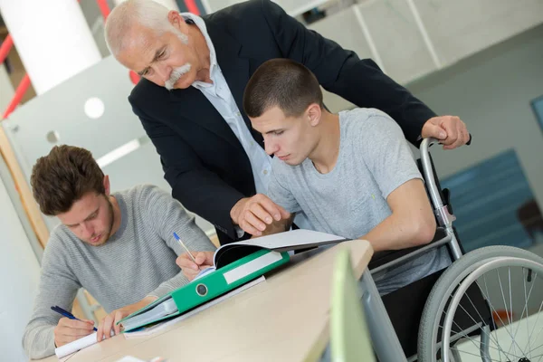 Student i rullstol arbetar i rättslig hjälp klass — Stockfoto