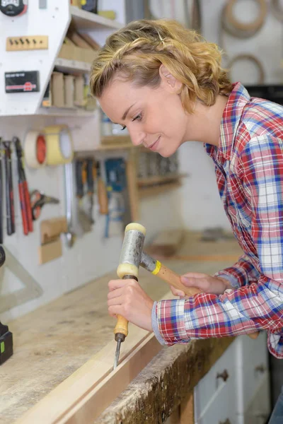 Vrouwelijke artiest beitels een houten sculptuur — Stockfoto