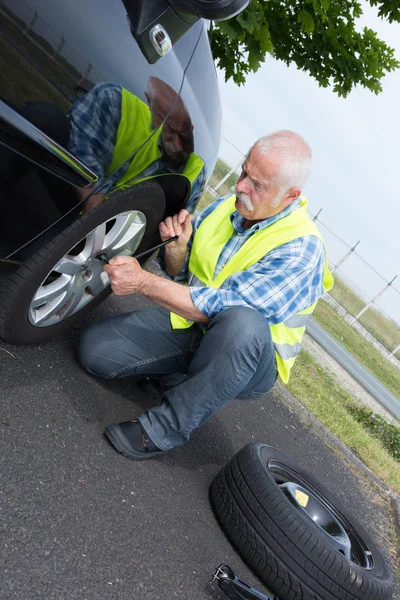 Retired man has to change punctured wheel — Stock Photo, Image