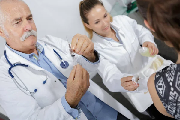 Senior male doktor håller en spruta — Stockfoto