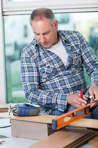 Hombre mayor en el taller con nivel de espíritu y rompecabezas — Foto de Stock