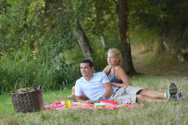 Pareja de jóvenes amantes teniendo un picnic —  Fotos de Stock