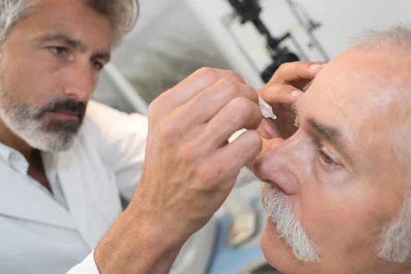 Met behulp van de dalingen van het oog van de mydriatics naar de verkleumd van de ogen van een optometrist — Stockfoto