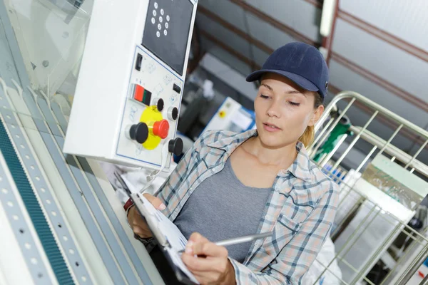 Kvinnliga lärling ingenjör som arbetar på maskin i fabriken — Stockfoto