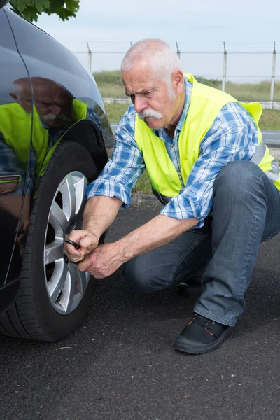 Retired man has to change punctured wheel — Stock Photo, Image