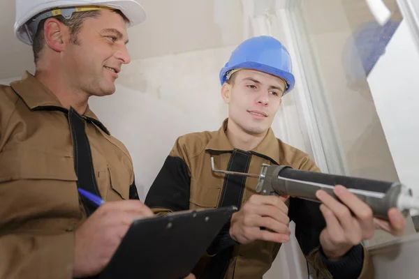 Lehrling erneuert Silikonfuge am Fenster — Stockfoto