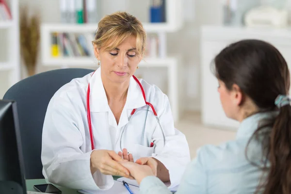 Maturo medico femminile guardando le mani dei suoi pazienti — Foto Stock