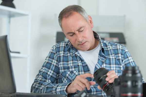 Técnico que examina e repara a câmera dslr — Fotografia de Stock
