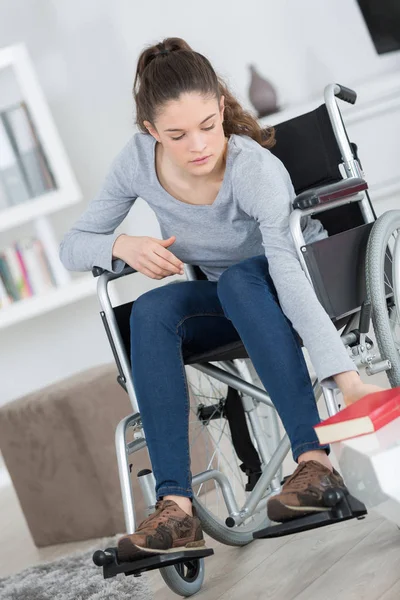 Νεαρή γυναίκα κάθεται σε αναπηρική καρέκλα φθάνοντας ένα βιβλίο — Φωτογραφία Αρχείου