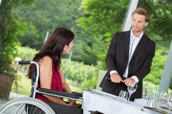 Mujer en silla de ruedas lista para pedir en un restaurante —  Fotos de Stock