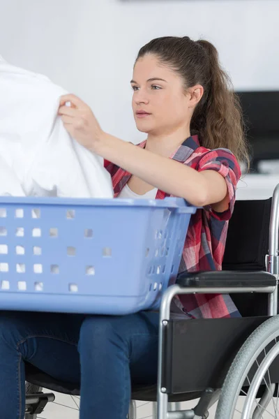 Jonge gehandicapte vrouw op rolstoel met behulp van wasmachine — Stockfoto