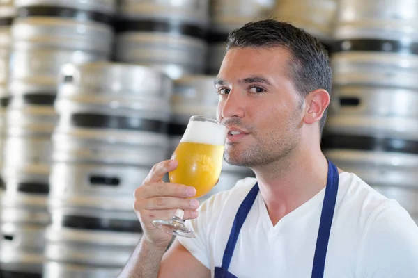 Apuesto joven cervecero masculino en delantal degustación de cerveza fresca —  Fotos de Stock