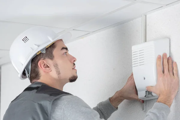 Eletricista masculino instalando sensor de porta do sistema de segurança na parede — Fotografia de Stock