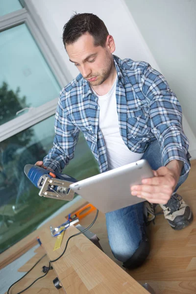 Carpenter using a tablet to instal a laminate flooring — Stock Photo, Image
